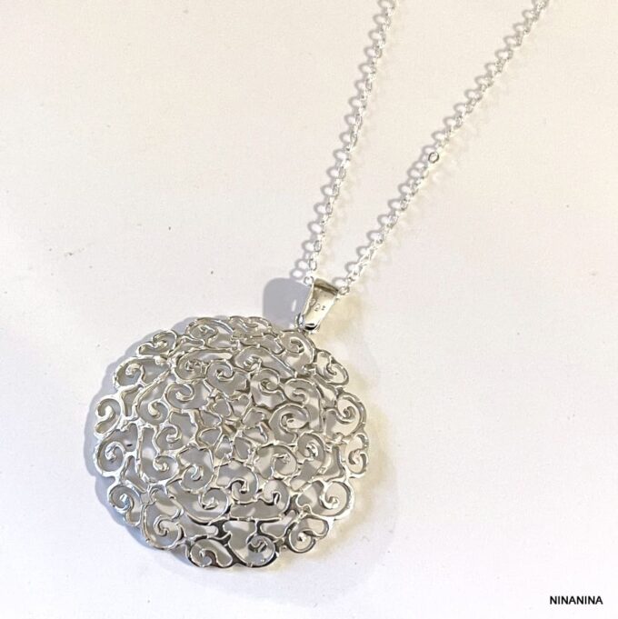 Détails en gros plan du Pendentif rond en argent sterling ajouré, collier raffiné pour femme signé Ninanina sur fond blanc