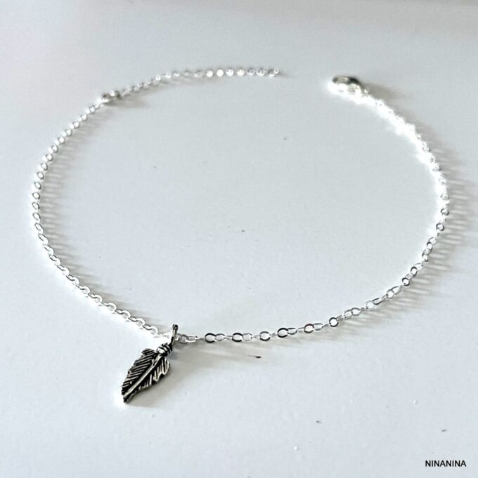 Zoom sur la chaîne de cheville en argent 925 avec pendentif plume sur fond blanc - Bijou artisanal raffiné pour femme