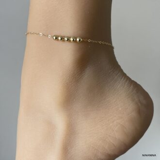 Chaîne de cheville femme de 27 cm avec perles rondes en plaqué or porté en gros plan - Bijou élégant et raffiné signé Ninanina