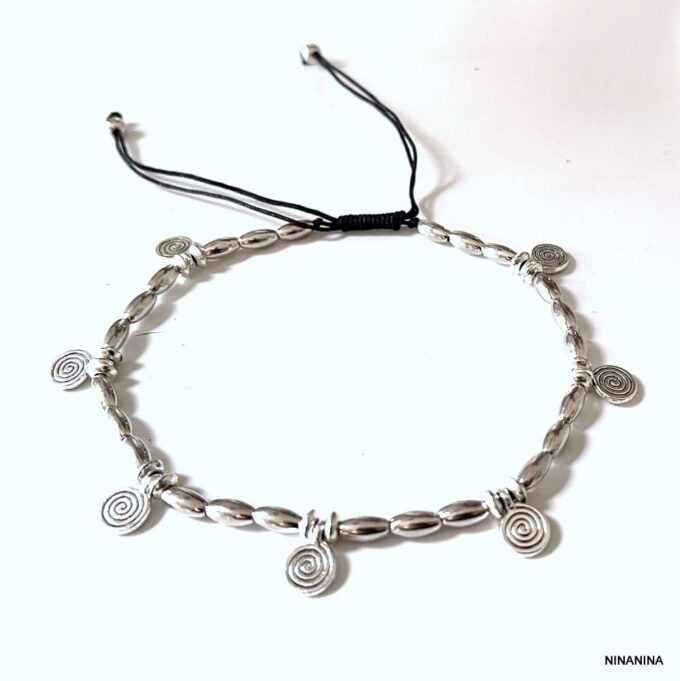 Gros plan sur Bracelet de cheville bohème chic fait main, orné de spirales et perles ovales argentées sur fond blanc, bijou raffiné Ninanina