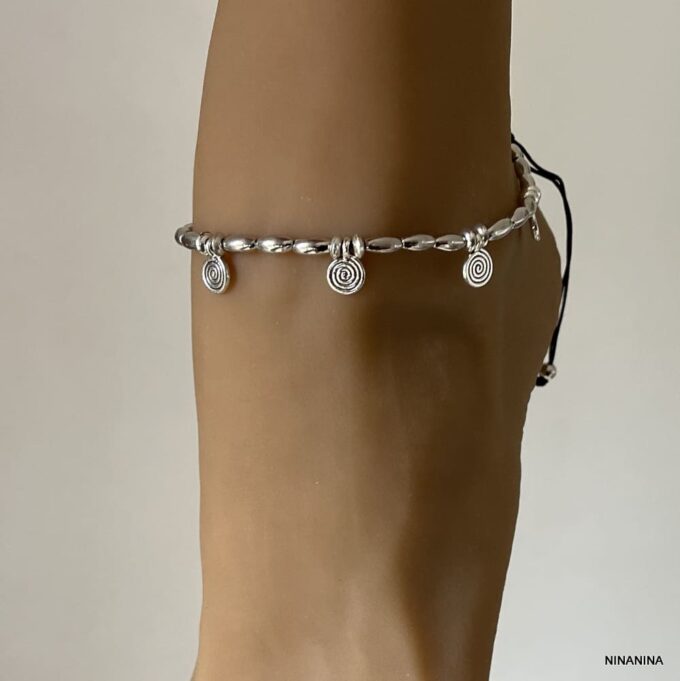 Bracelet de cheville artisanal argenté au design bohème chic avec motifs spirales et perles ovales argentées porté