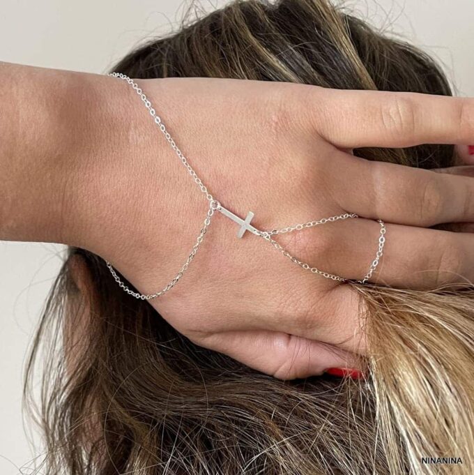 Bracelet bague gothique avec chaîne pour main et motif croix en argent porté par une main posée derrière la tête, création Ninanina