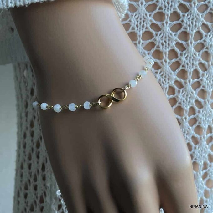N6498 Bracelet Pierre Lune Blanche Signe Infini Plaqué Or Femme - Bijoux Bracelets femmes en ligne Ninanina Bracelet femme en pierre de lune blanche et signe infini plaqué or porté sur une main de femme - Bijou artisanal raffiné disponible chez Ninanina