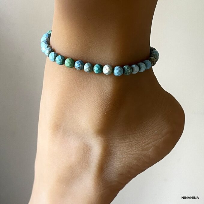 Zoom sur le bracelet de cheville femme en perles à facettes bleu turquoise porté sur un pied de profil - Bijou raffiné et fait main