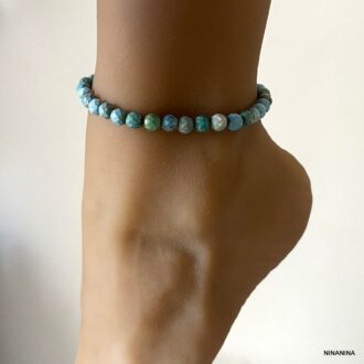 Bijou artisanal : bracelet de cheville avec perles bleu turquoise à facettes porté sur un pied de mannequin - Accessoire chic signé Ninanina