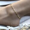 Bracelet de cheville or plaqué femme – chaine losange doré de Ninanina porté sur un pied posé sur un hamac blanc