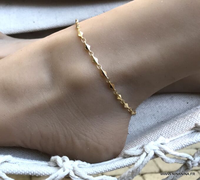 Bracelet de cheville or plaqué femme – chaine losange doré de Ninanina porté sur un pied posé sur un hamac blanc