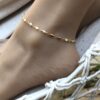 Bracelet de cheville or plaqué femme – chaine losange doré de Ninanina porté sur un pied posé sur un hamac blanc