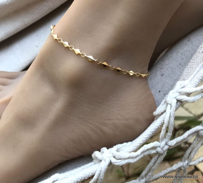Bracelet de cheville or plaqué femme – chaine losange doré de Ninanina porté sur un pied posé sur un hamac blanc