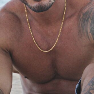 Gros plan sur Chaîne vénitienne plaqué or pour homme portée par un homme musclé et tatoué, fabriquée en acier résistant, look sophistiqué