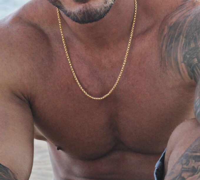 N7038a Chaine maille venitienne or plaqué sur Acier pour homme - Bijoux Chaines en ligne Ninanina Gros plan sur Chaîne vénitienne plaqué or pour homme portée par un homme musclé et tatoué, fabriquée en acier résistant, look sophistiqué