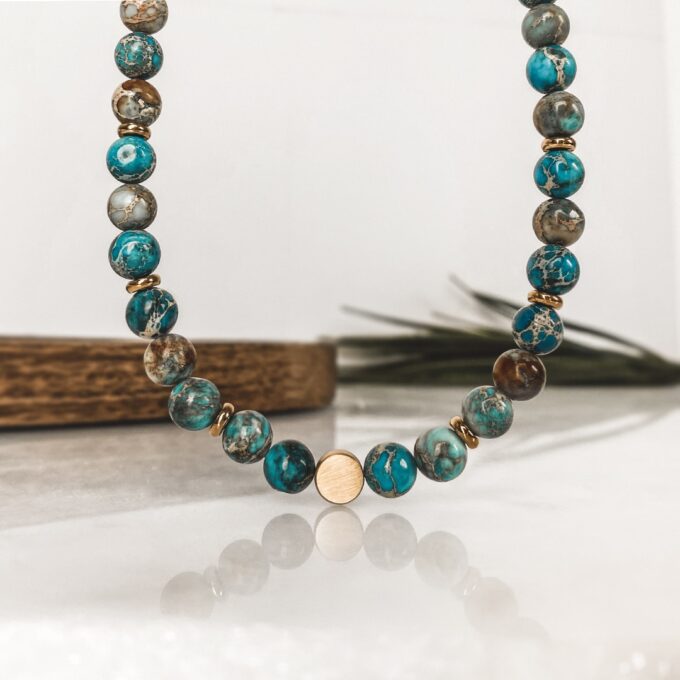 N7994d Collier Pierre Naturelle Homme Jaspe Bleu Hématite Or - bijoux Colliers en ligne Ninanina Laissez-vous séduire par l’élégance et la sobriété de ce Collier Pierre Naturelle Homme Jaspe Bleu Hématite Or  ! Long de 45 cm, il se compose de perles rondes en jaspe bleu et de rondelles en hématite doré et se termine par un fermoir solide qui garantit un ajustement sécurisé et confortable. Les perles de jaspe bleu de 8 mm de diamètre sont soigneusement sélectionnées pour leur couleur vibrante et leur finition lisse. Chaque perle est polie à la main pour créer une surface brillante et agréable au toucher. Les perles d'hématite dorée ajoutent une touche de luxe et de sophistication à l'ensemble. La combinaison du jaspe bleu et de l'hématite crée un contraste saisissant qui attire le regard.