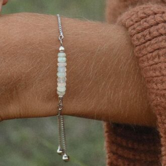Gros plan sur Bracelet En Jade Blanc Pierres 6mm Et Acier Réglable fait main en france signé Ninanina porté sur un poignet bronzé