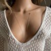 Bijou artisanal pour femme, collier infini en gold filled 14k avec design élégant, accessoire élégant porté avec une robe blanche crochetée à décolleté plongeant, idéal pour un style bohème chic.