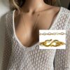 Collier infini en or laminé gold filled 14k, sautoir féminin fait main signé Ninanina, accessoire élégant porté avec une tenue blanche crochetée à décolleté plongeant, idéal pour un style bohème chic.