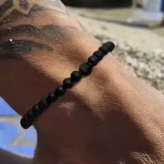 Zoom sur le bracelet de cheville en pierre de lave volcanique noire pour homme porté - Accessoire chic et robuste fabriqué en France