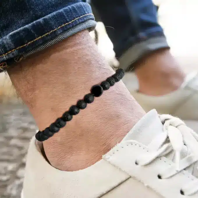 N8230a Bracelet Cheville Noir Homme Pierre De Lave Volcanique - Bijoux de pieds hommes en ligne Ninanina Bracelet de cheville noir pour homme en pierre de lave volcanique porté - Bijou artisanal fait main en France signé Ninanina