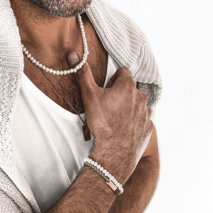 Collier en perles naturelles blanches porté par un homme - Bijou chic et moderne pour compléter une tenue.