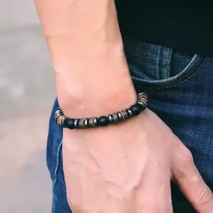 Bracelet Heishi Homme Hematite Onyx Noir Et Bois Fait Main En France de Ninanina porté par un homme avec la main qui pend le long de son pantalon