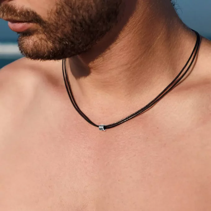 N8295a Collier Cordon Noir Artisanal Perle Cylindrique Acier Inox Made In France - Bijoux Colliers hommes en ligne Ninanina Gros plan sur le Collier Cordon Noir Artisanal Perle Cylindrique Acier Inoxydable artisanal Made In France porté par un homme barbu torse nu