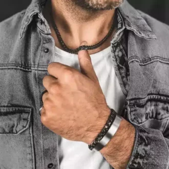 Chaine Acier Noir 7mm Homme Maille Gourmette 55cm faite main portée par un homme qui tient la chaine avec son pouce